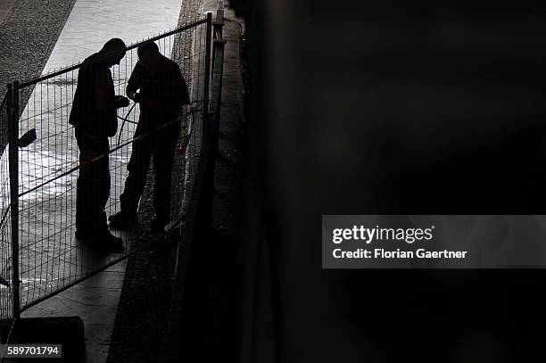 The silhouette of two working men are captured on August 04, 2016 in Berlin, Germany.