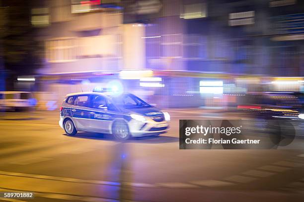 Police car drives over a crossroad with emergency lights at night on August 09, 2016 in Berlin, Germany.