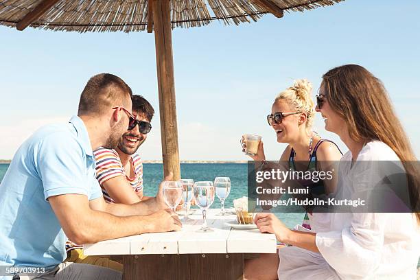 group of friends relaxing in beach bar - beach clear sky stock pictures, royalty-free photos & images