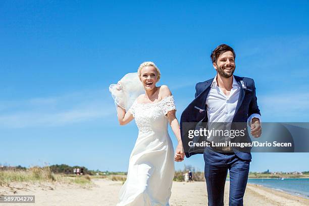 bride and bridegroom on beach having fun - bride running stock pictures, royalty-free photos & images