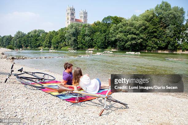 happy young couple relaxing on the riverbank - munich stock pictures, royalty-free photos & images