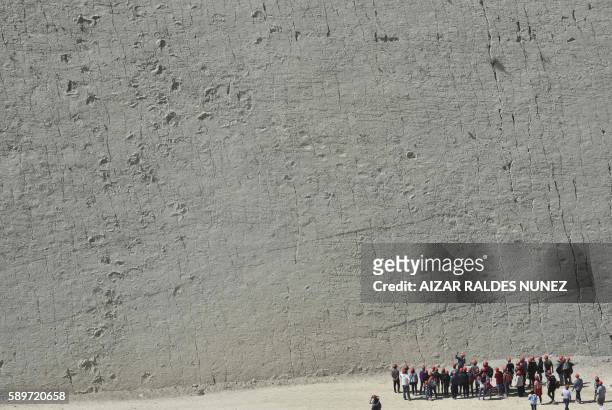 Tourists watch dinosaur footprints at the Cal Orcko Cretaceous Park in Sucre, Bolivia on August 7, 2016.