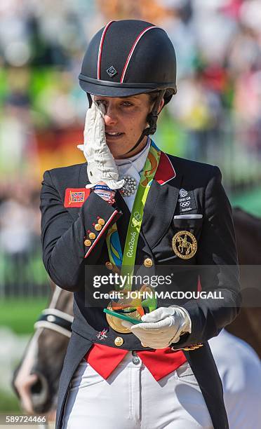 Britain's Charlotte Dujardin wipes a tear after receiving her gold medal during a victory ceremony after the Equestrian's Dressage Grand Prix...