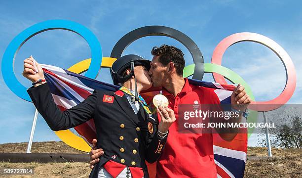 Britain's Charlotte Dujardin kisses her fiance Dean Golding as she poses with her gold medal in front of the Olympic rings after the Equestrian's...