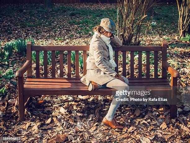 elegant woman sitting on a bench at the park - deerstalker stock pictures, royalty-free photos & images