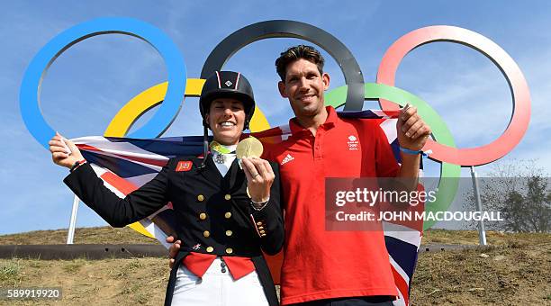 Britain's Charlotte Dujardin poses with her fiance Dean Golding and her gold medal in front of the Olympic rings after the Equestrian's Dressage...