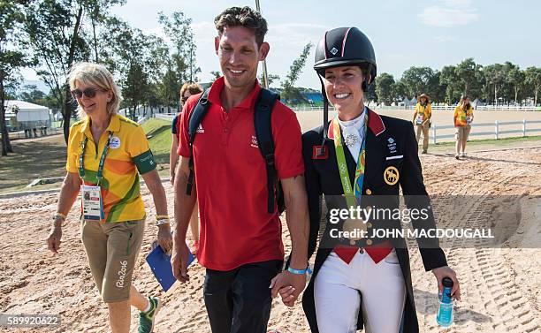 Britain's Charlotte Dujardin , carrying her gold medal, and her fiance Dean Golding, walk hand in hand after the Equestrian's Dressage Grand Prix...