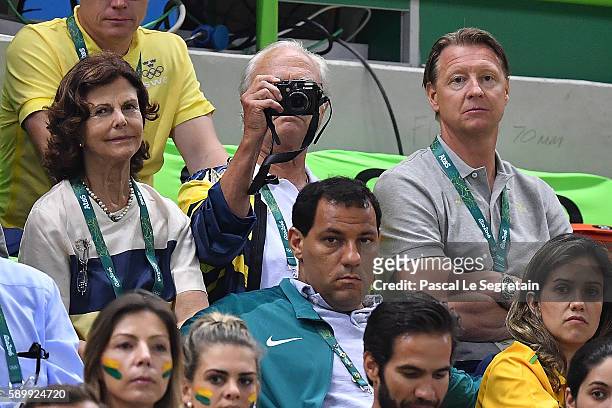 King Carl Gustaf of Sweden takes a picture as Queen Silvia of Sweden and Swedish Olympic Committee President Hans Vestberg sit next to him during the...