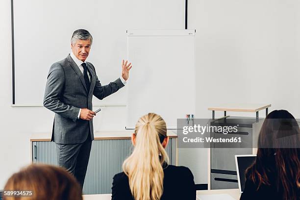 mature man giving business presentation - man flipchart stock pictures, royalty-free photos & images