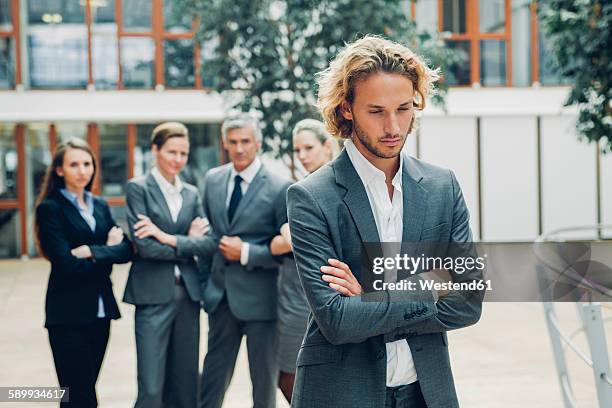 businessman with crossed arms, excluded from group of business people - unfair competition stock pictures, royalty-free photos & images