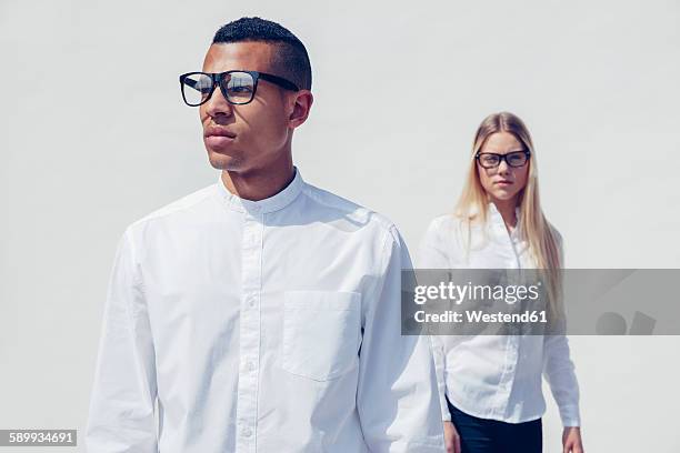 portrait of stylish young couple wearing matching clothes in front of white background - man white background photos et images de collection