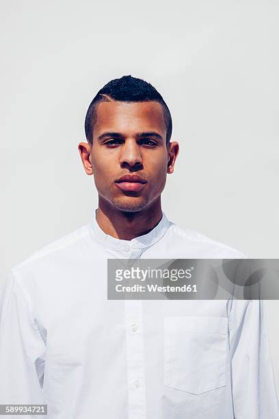 portrait of young man with shaved hair wearing white shirt in front of white background - man plain background stock pictures, royalty-free photos & images