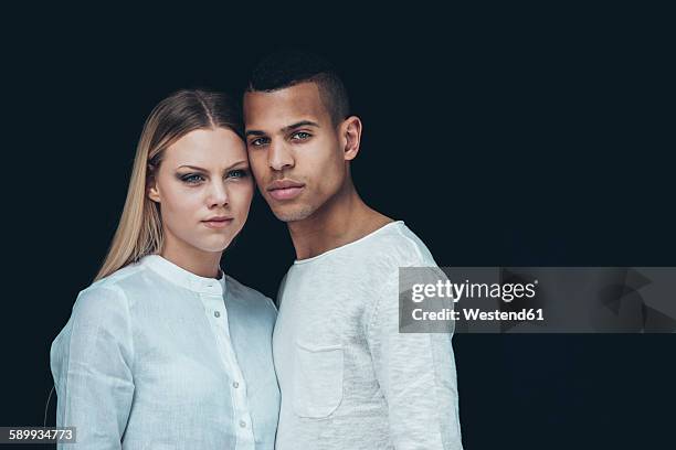 portrait of young couple wearing white clothes head to head in front of black background - couple dark background bildbanksfoton och bilder