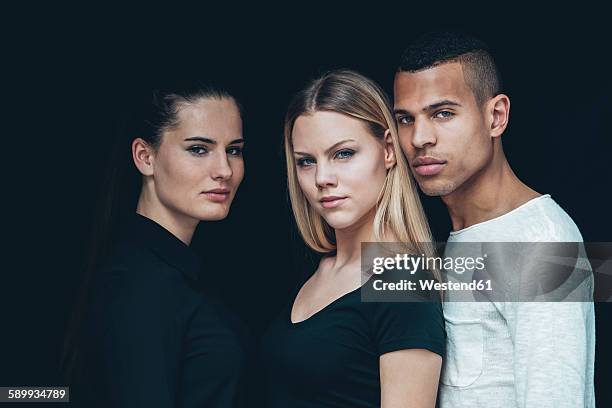 group picture of two young woman and young man in front of black background - couple dark background stock pictures, royalty-free photos & images