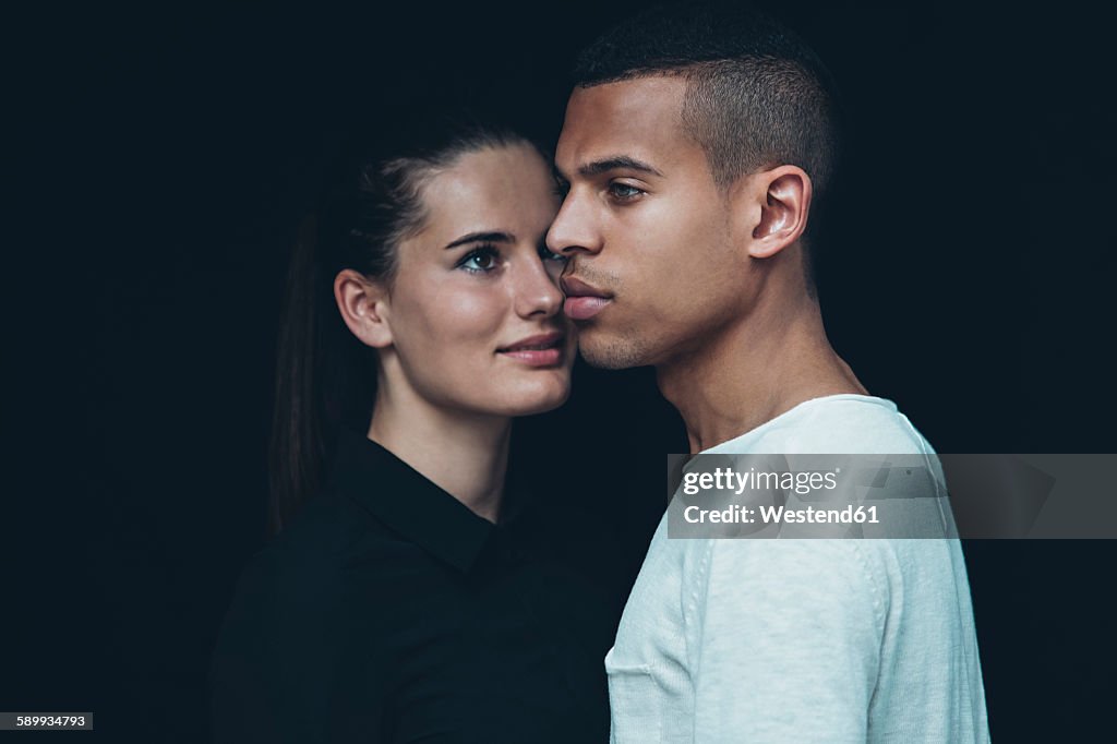 Portrait of young couple head to head in front of black background