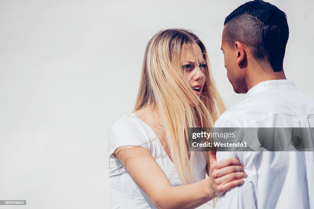 Portrait of angry young woman face to face with her boyfriend in front of white background