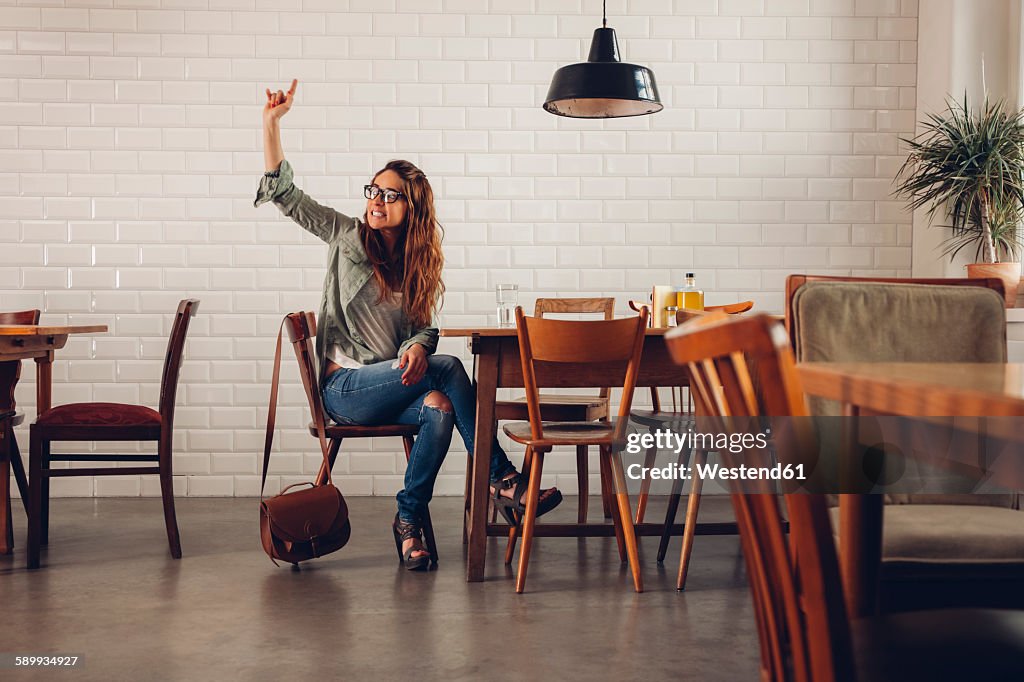 Young woman in restaurant calling for waiter