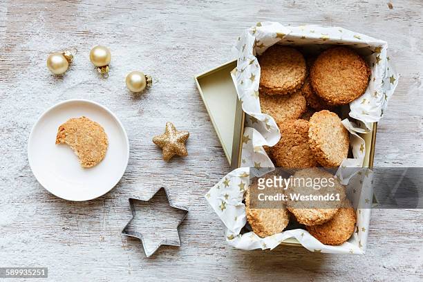 box of whole grain cocos cookies, christmas decoration and cookie cutter on wood - coconut biscuits stockfoto's en -beelden