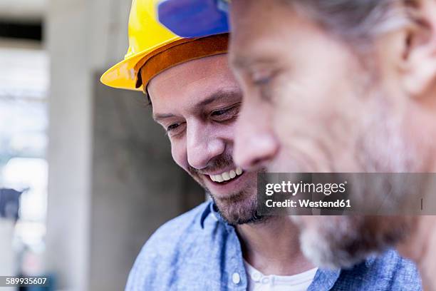 close-up of two smiling men on construction site - laborer stock-fotos und bilder