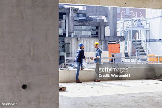 two men with hard hats talking on construction site - construction material stock-fotos und bilder