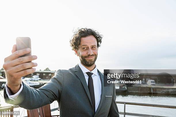 germany, luebeck, businessman at harbor taking a selfie - arrogant stock-fotos und bilder
