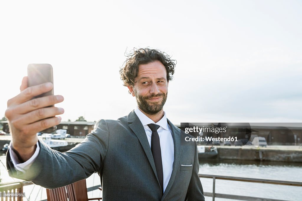 Germany, Luebeck, businessman at harbor taking a selfie