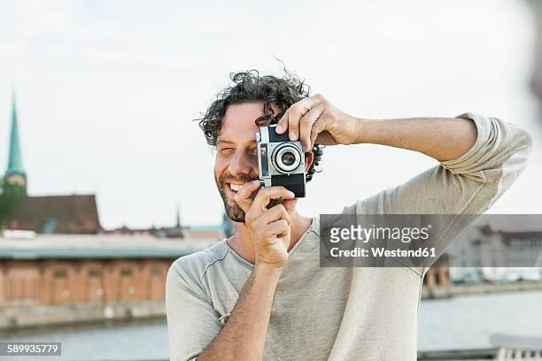 germany, luebeck, man taking picture at the waterside - photographer stock-fotos und bilder