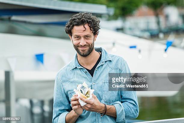 smiling man holding a fish sandwich - roll shirt stock pictures, royalty-free photos & images