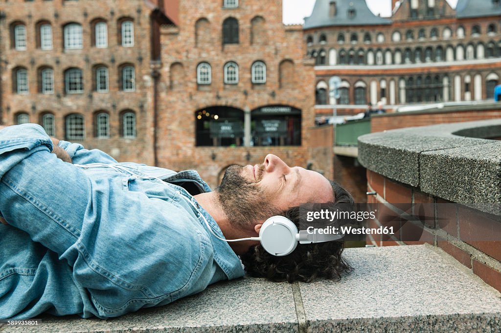 Germany, Luebeck, man with headphones relaxing in the city