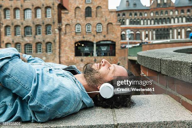 germany, luebeck, man with headphones relaxing in the city - music enjoyment stock pictures, royalty-free photos & images