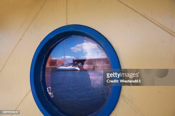 germany, luebeck, man behind porthole at harbor - lübeck stock-fotos und bilder