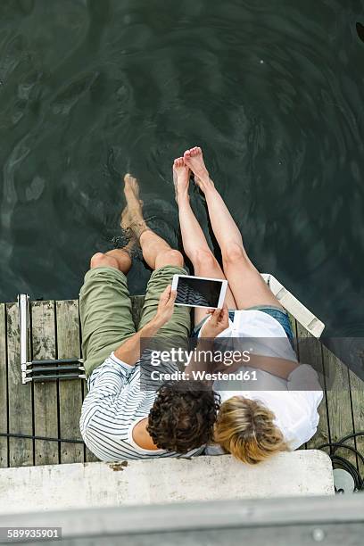 couple sharing digital tablet at the water - tablet paar sommer stock-fotos und bilder