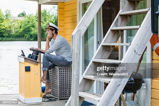 man wearing captain's hat having a trip on a house boat - sailor hat 個照片及圖片檔