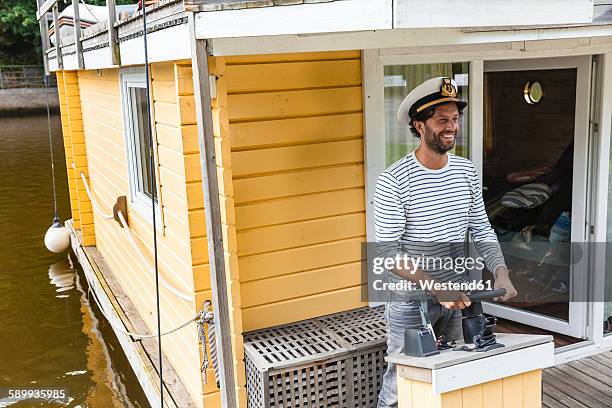 man wearing captain's hat having a trip on a house boat - bootskapitän stock-fotos und bilder