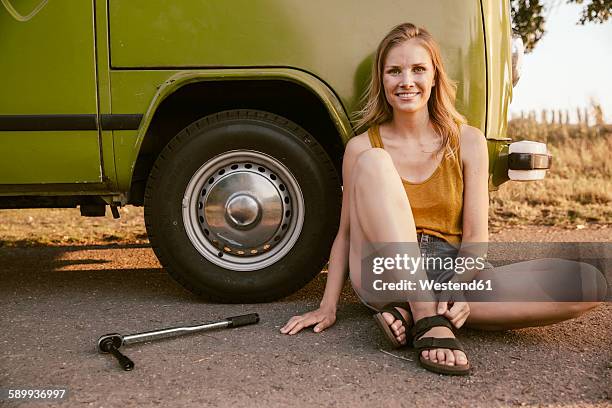 smiling woman sitting next to a torque wrench at van - flat tyre stock pictures, royalty-free photos & images