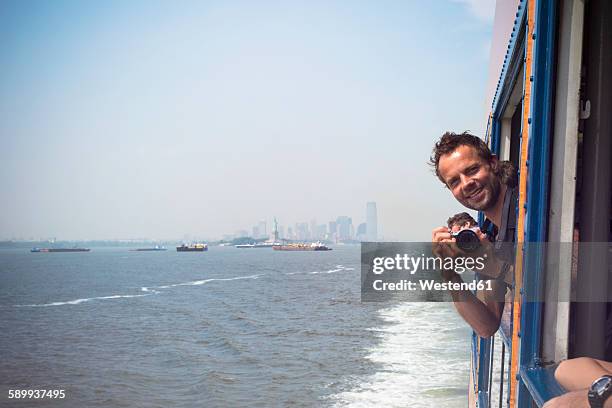 usa, new york city, tourist with camera on staten island ferry with view of manhattan skyline and east river - staten island ferry - fotografias e filmes do acervo