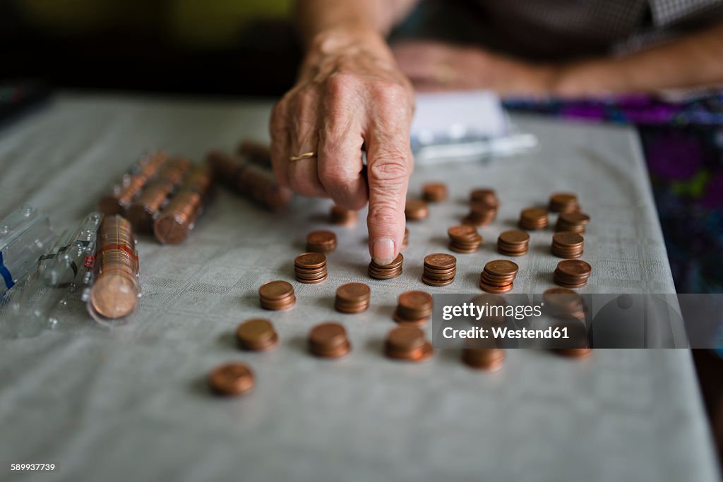 Elderly woman counting money, making stacks of Euro cents