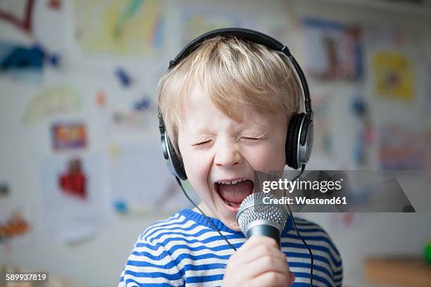 portrait of singing little boy with headphones and microphone - boy singing stock-fotos und bilder