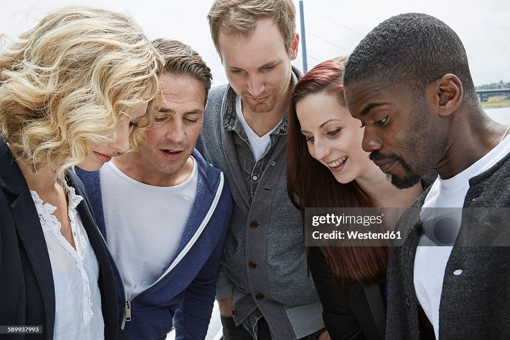 Group of friends outdoors looking down at something