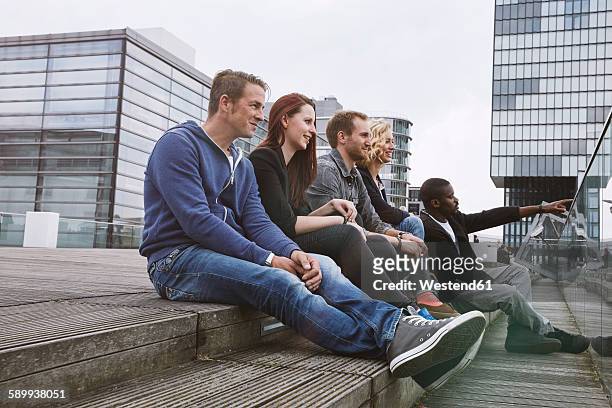 group of friends sitting outdoors on stairs - north rhine westphalia stock-fotos und bilder
