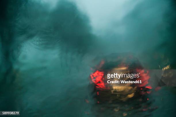 blurred view through windscreen by storm at twilight - rear light car stock pictures, royalty-free photos & images