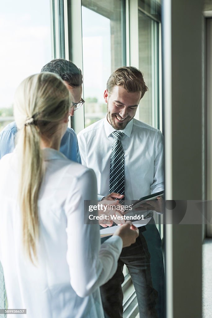 Three young businesspeople looking at documents and digital tablet