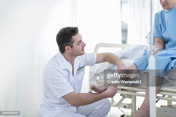 nurse applying bandage to senior patient's leg in hospital - applying bandage stock pictures, royalty-free photos & images