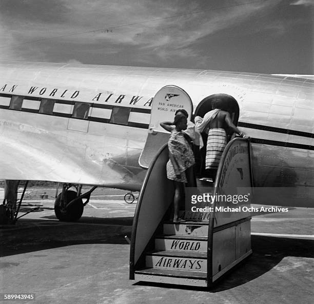 Group of Maroon People enter the Pan American World Airways Clipper DC4 plane, before taking a trip at the Paramaribo-Zanderij International Airport...
