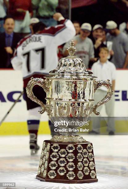 Ray Bourque of the Colorado Avalanche pumps his fist in the background as he leaves the ice behind the Western Conference Clarence Campbell Trophy...