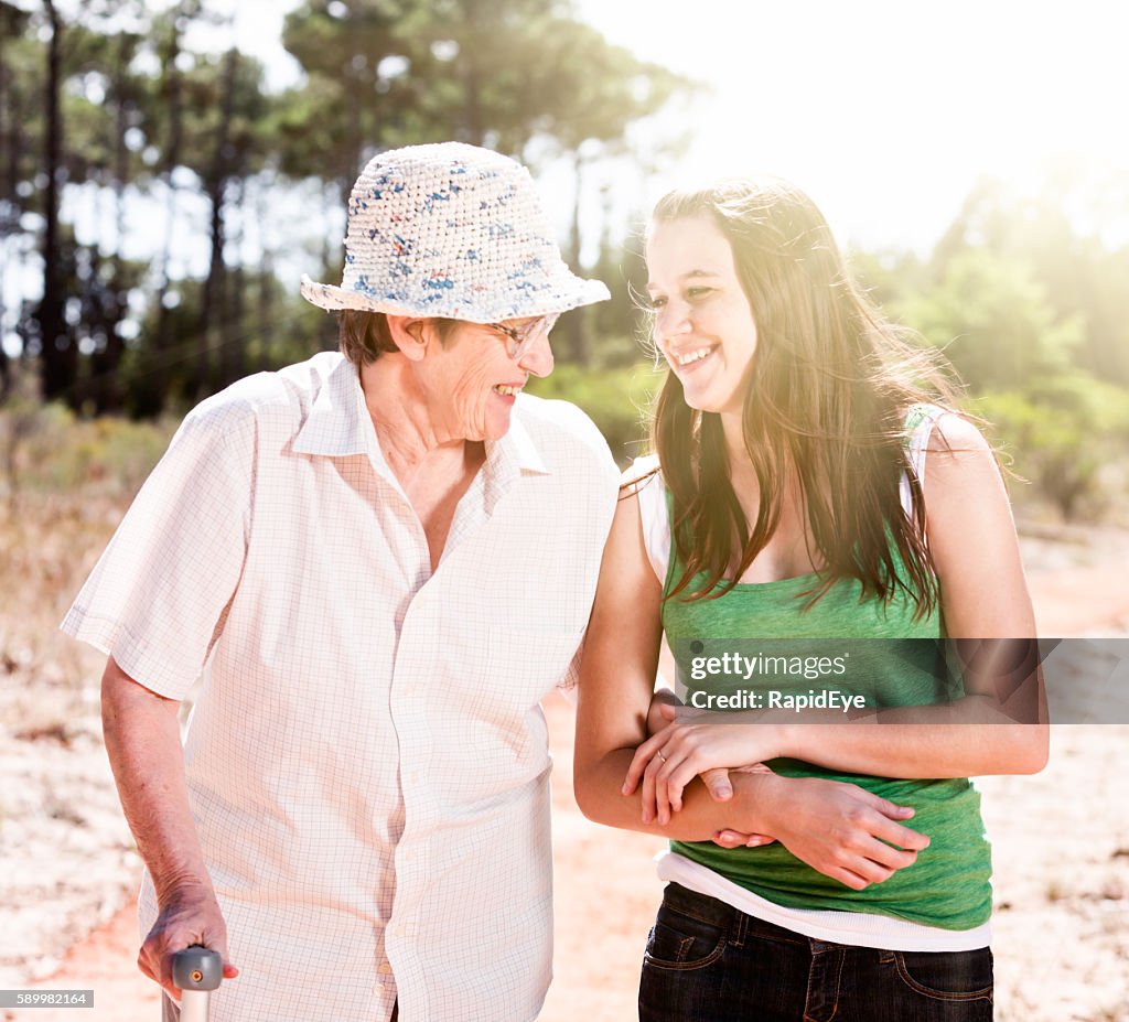 Junge und alte Frau, Arm in Arm, gehen, lächeln einander an