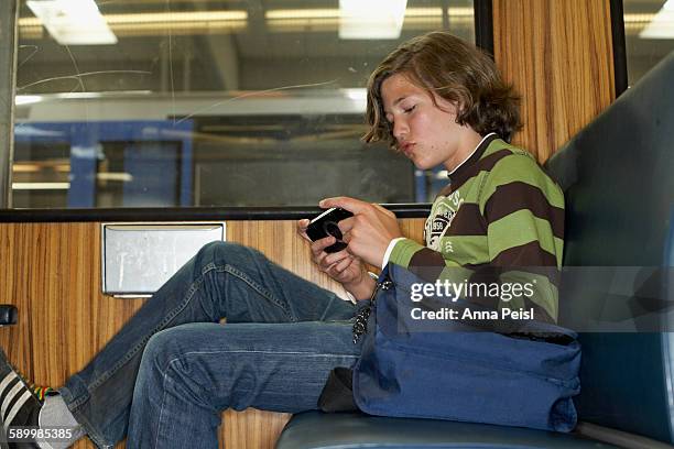 teenage boy on subway playing handheld video game - pocket electronic game stock pictures, royalty-free photos & images