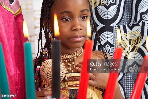 young girl looking at kwanzaa candles - kwanzaa celebration stock pictures, royalty-free photos & images
