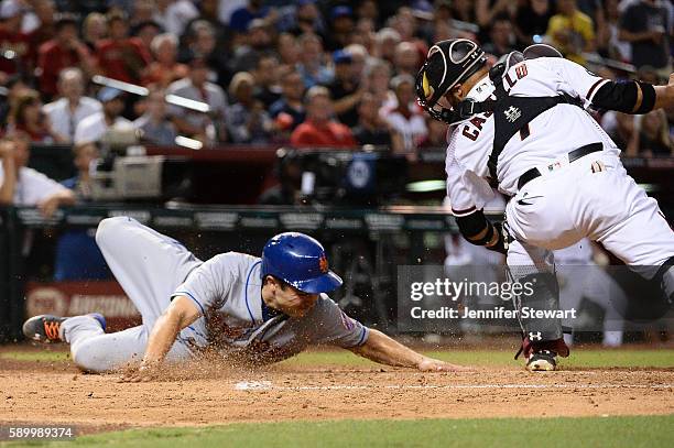 Travis d'Arnaud of the New York Mets safely slides into home plate against Welington Castillo of the Arizona Diamondbacks during the fourth inning at...