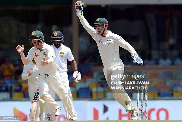 Australia's wicketkeeper Peter Nevill and teammate David Warner celebrate after the dismissal of Sri Lanka's Kusal Perera during the fourth day of...